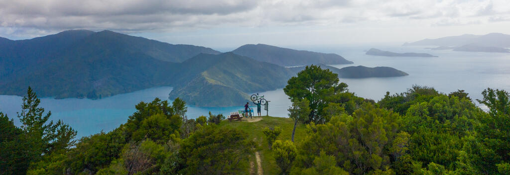 Cyclists admiring scenic view of lake and mountains at the top og the Queen Charlotte Track