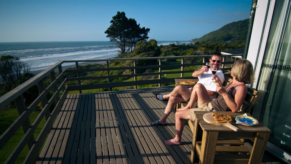 Guests enjoying homemade pizza on the deck with views to Tasman Sea
