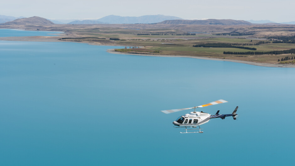 Heli flying over turquoise blue Lake Tekapo