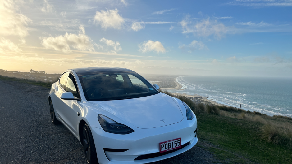 GO Rentals Tesla Model 3 vehicle parked along the side of the road overlooking Taylor's Mistake beach.