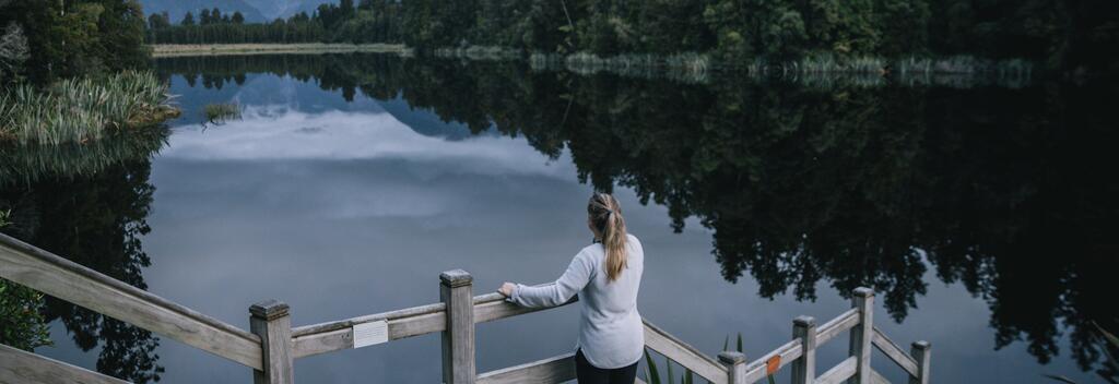 Woman on wooden platform looking at Lake Matheson 