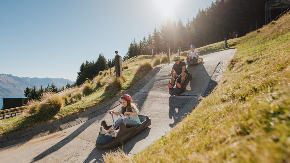 A family rides down a steep section on the Red Luge track.