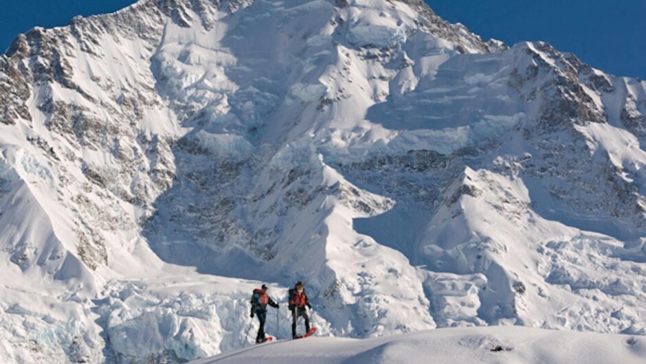Snowshoers in front of the Caroline Face of Aoraki Mount Cook.
