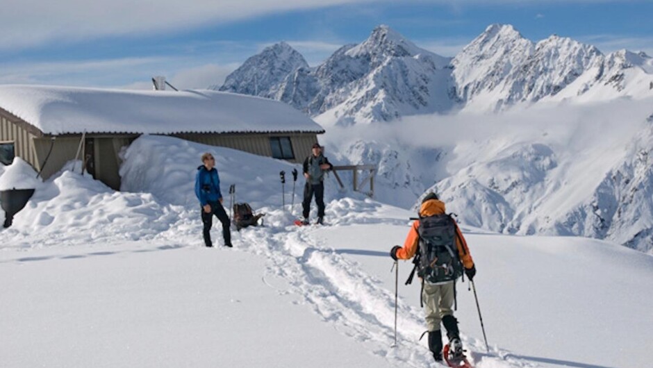 Snowshoers return to Caroline Hut after an ascent of Kaitiaki Peak in winter.