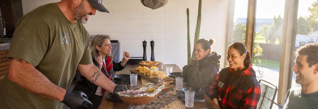 Deon Muir serving food to guests in Maketū, Bay of Plenty. 