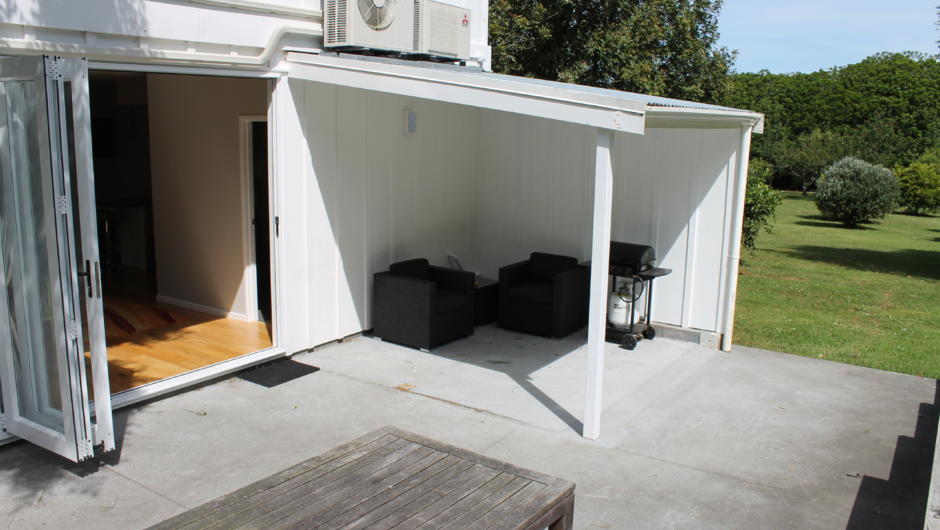 Patio area and covered comfortable outdoor seating with BBQ overlooking the orchard and paddocks at the back of the 2-bedroom apartment.