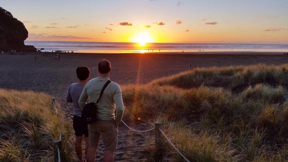 Couple viewing the beautiful sunset on New Zealand beach.