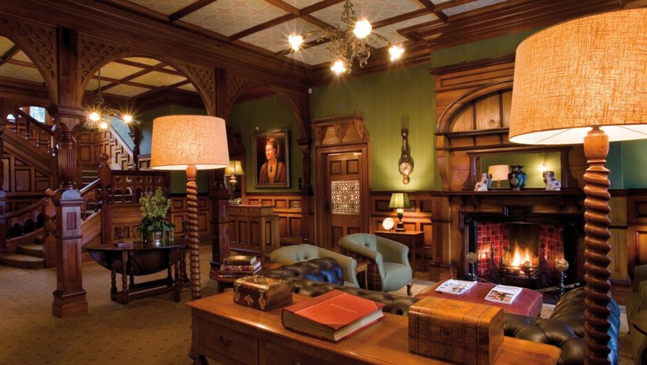 The Entry Hall at Otahuna Lodge features original Rimu paneling, New Zealand artworks, and a grand staircase.