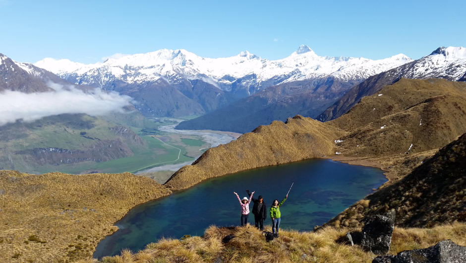 A group enjoying the stunning views out over an alpine lake, the Matukituki Valley and Mount Aspiring National Park.