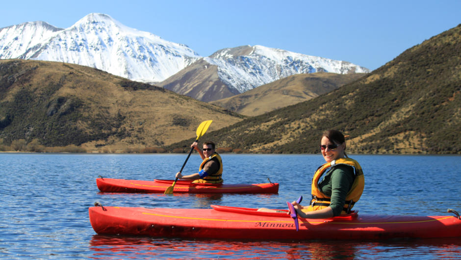 Kayak tranquil alpine lakes beneath towering mountain peaks.