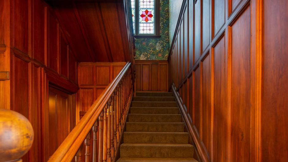 The stairs lead up to the first floor from the paneled hallway.
