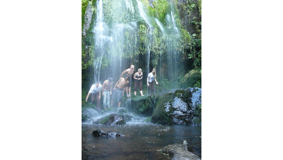 A group of friend enjoying a waterfall of the forest.