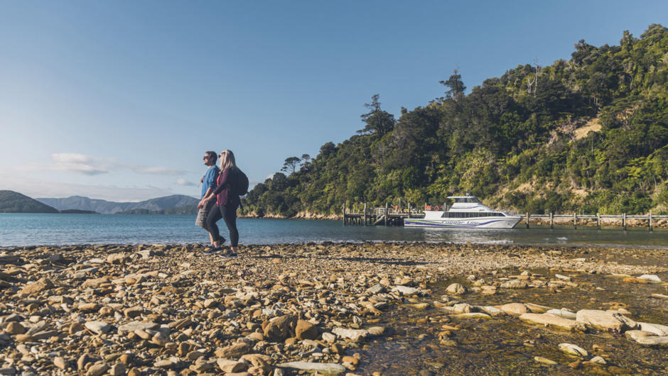 Couple walking along Ship Cove beach on way to Queen Charlotte Track.