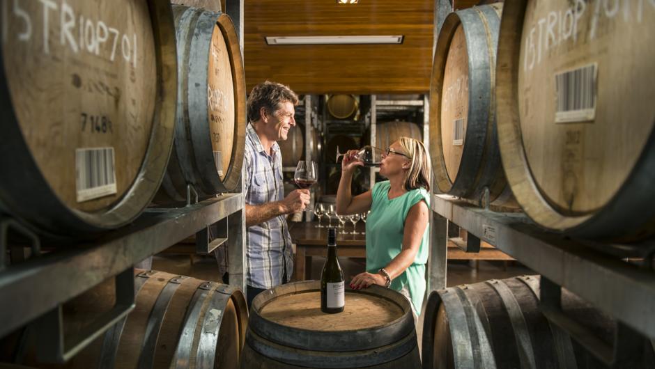 Couple enjoying wine tasting in barrel cellar door