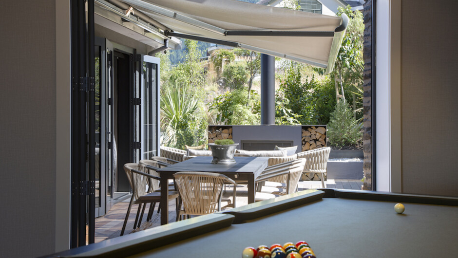 Pool table and outdoor patio with outdoor fireplace, lounge area and retractable awning over the outdoor dining area