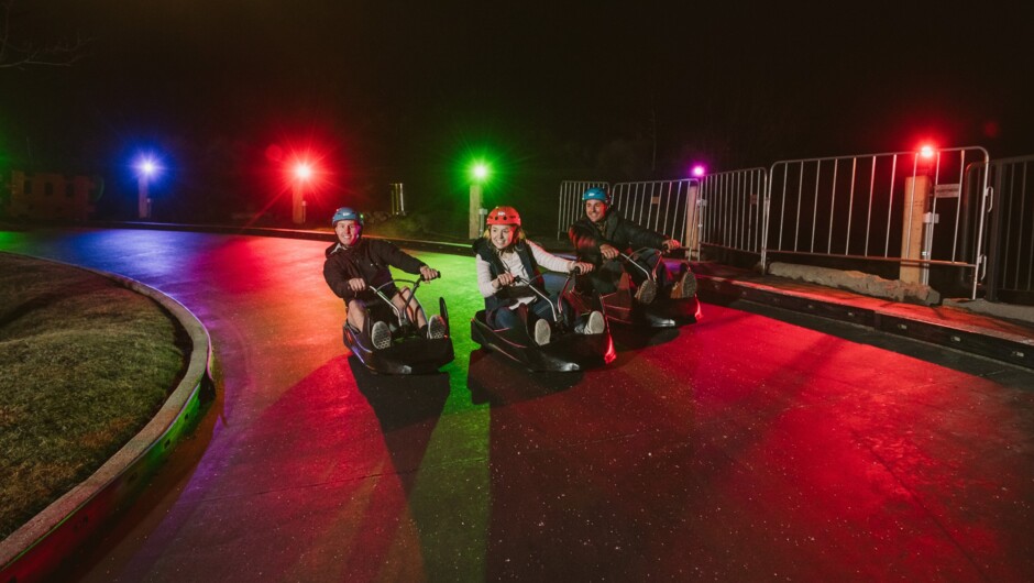 A group of friends riding the Night Luge.