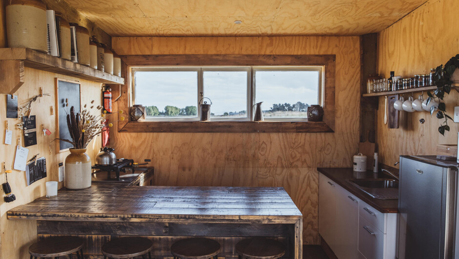Kawakawa Hut's kitchen and bar. The basic kitchen & bar make for a great area for enjoying food and drinks while looking out at Mt Ruapehu. A BBQ is just outside. The kitchen has a camp style gas cooker, a motorhome style fridge/freezer, coffee plunger, p