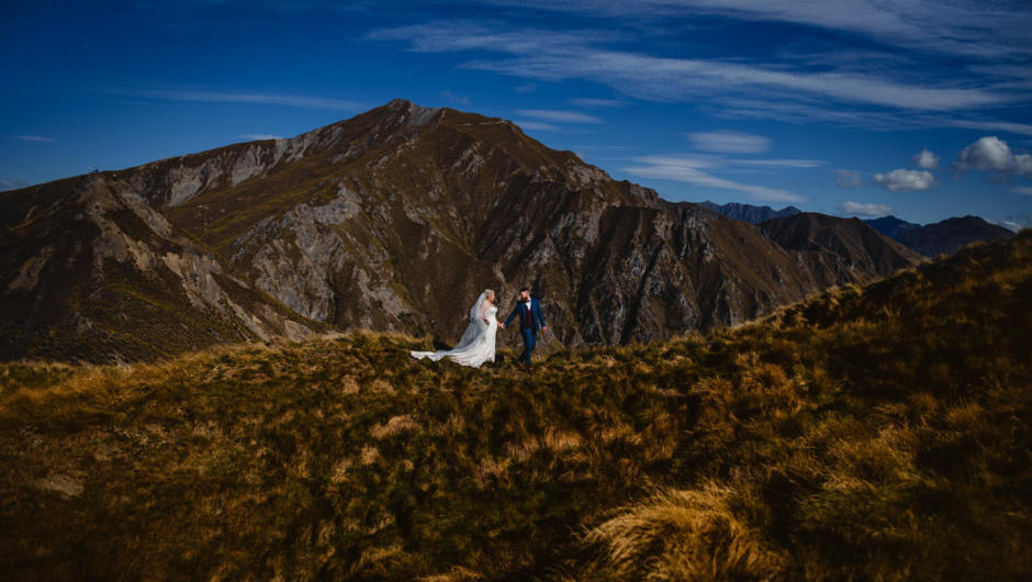 A couple exploring the hills above Wanaka on their wedding day.