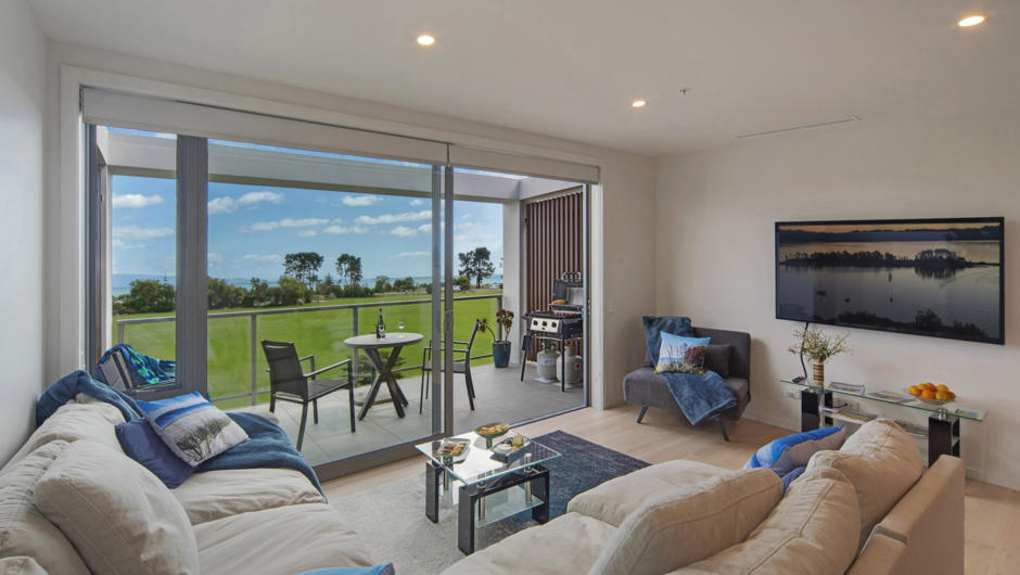 Spacious light-filled living area opening to outdoor balcony & views over the playing fields to Tasman Bay.