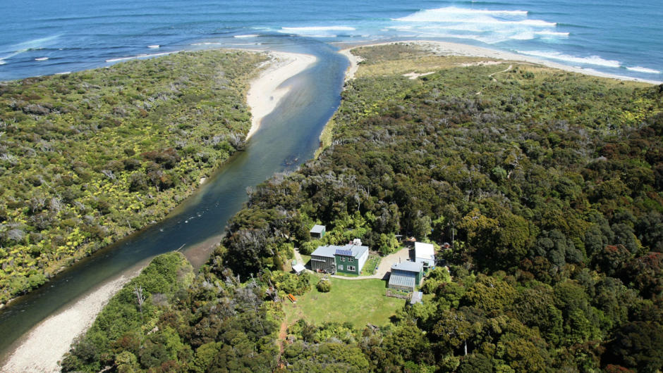 An aerial view of Waitutu Lodge with the Wairaurahiri River flowing alongside.