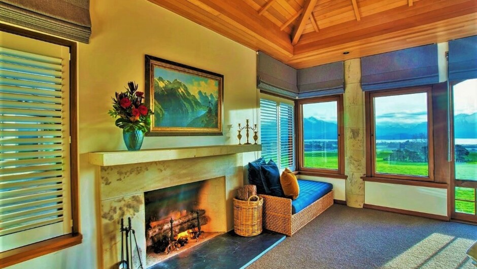 Interior of the Deluxe Suite at Cabot Lodge with open fireplace and views of the farm, Lake Manapouri and Cathedral Peak Mountains.