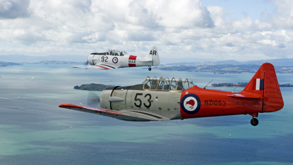 Two Second World War North American Harvards flying over the Waitemata Harbour near Maraetai.  NZ Warbirds at Ardmore has a number of this aircraft type on display which fly regularly.