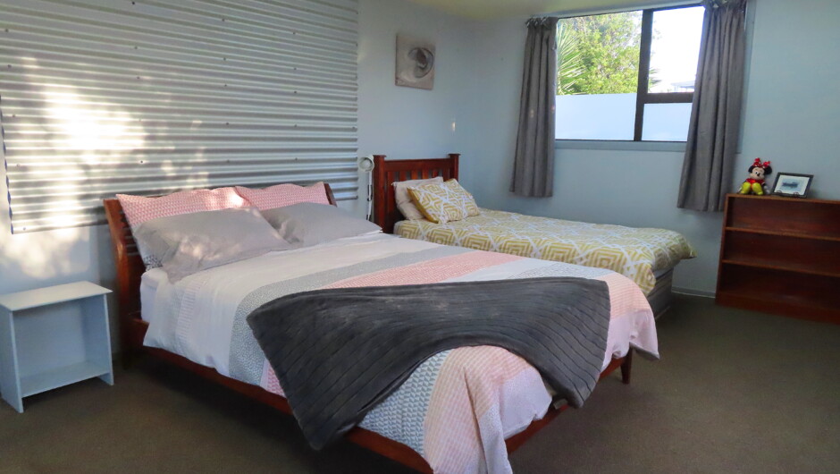 Larger bedroom with queen bed and set of king single beds.