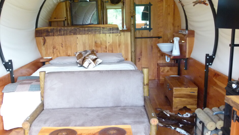 Super-king double bed and seating area. Shower and toilet room behind - Colonial Wagon, Wacky Stays, Kaikoura