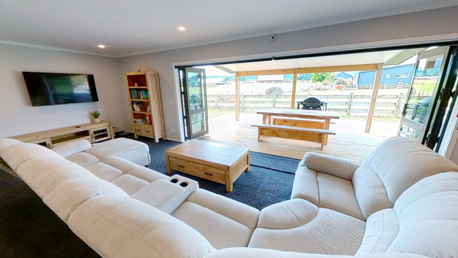 Lounge with big sofa, opening to entertainment deck and spa pool