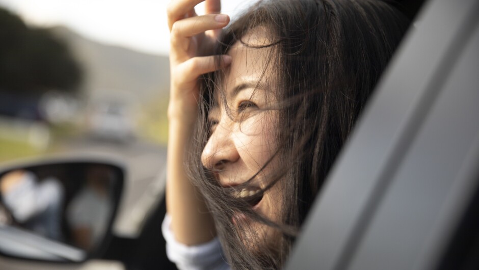 A woman smiling looking outside the passenger car window.