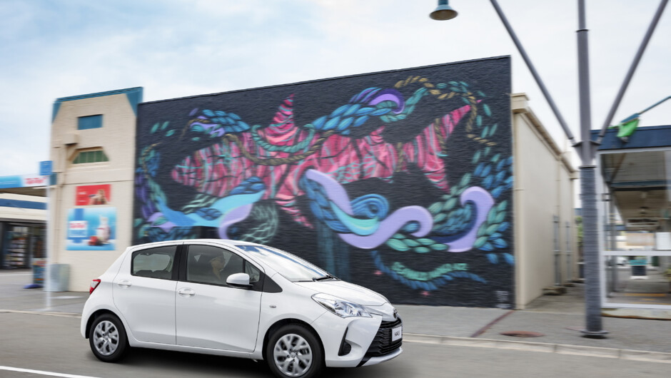 GO Rentals vehicle driving along Christchurch city road with a graffiti art wall in the background.