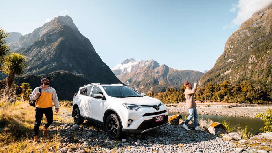 GO Rentals vehicle with two male persons standing beside vehicle admiring New Zealand&#039;s landscape.