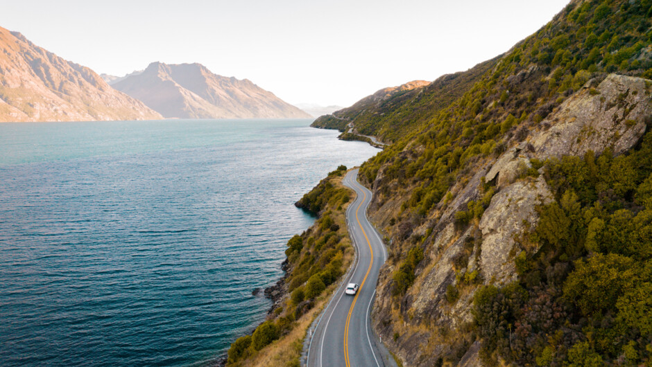GO Rentals car driving alongside the road in South Island with lake and mountain surroundings.
