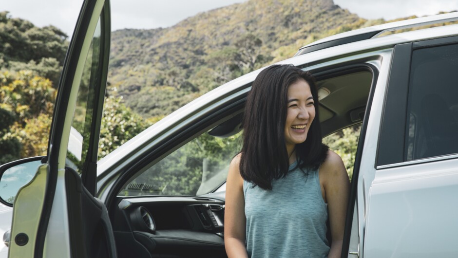 A woman smiling as she exits the passenger side of a GO Rentals car.