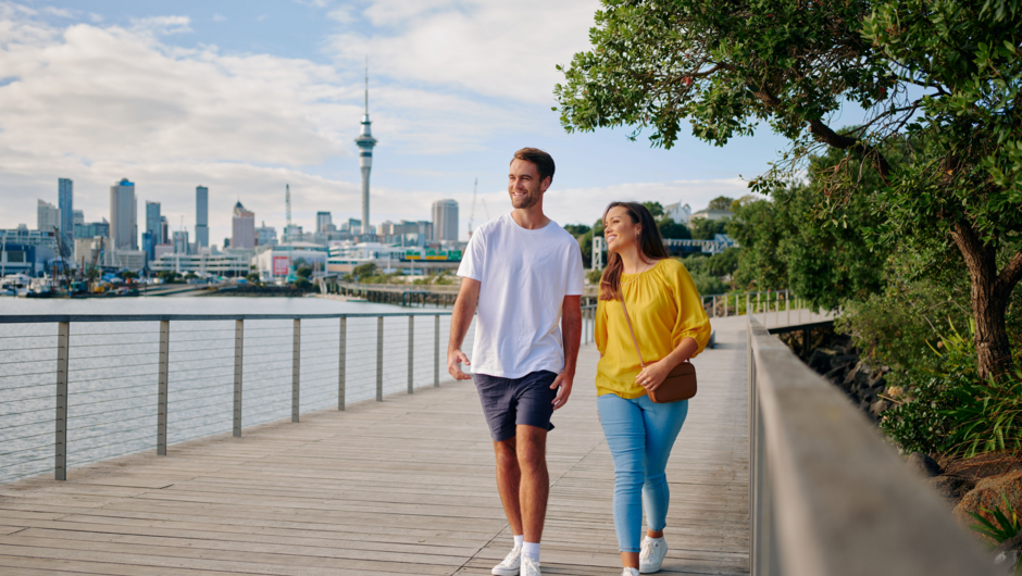 Couple walking along Westhaven Path with Sky Tower in background