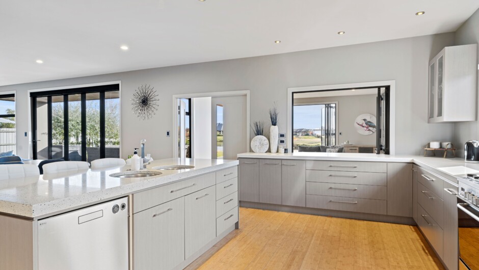 A generously designed open-plan kitchen, elegantly equipped with an oven, fridge, freezer, dishwasher, and a complete set of kitchen utensils and cutlery.