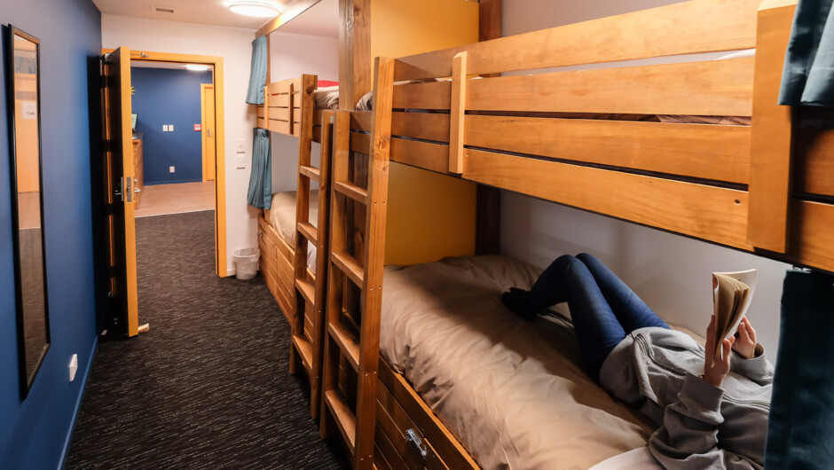 Dorm Room with custom bunks, privacy curtains, lockable storage, reading light and USB charger.