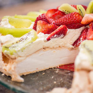 A classic Kiwi pavlova garnished with kiwifruit and strawberries.