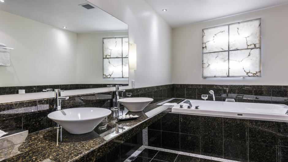 Marbled bathroom featuring a double sized indoor spa and a shower with twin massage heads