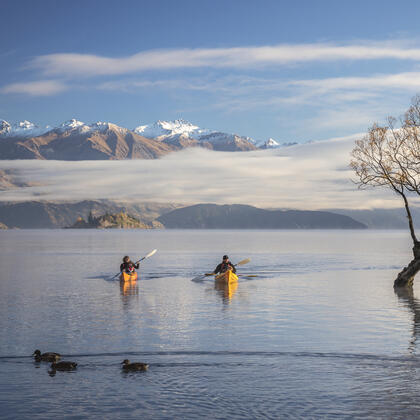 People kayaking on Lake Wānaka with scenic backdrop in New Zealand