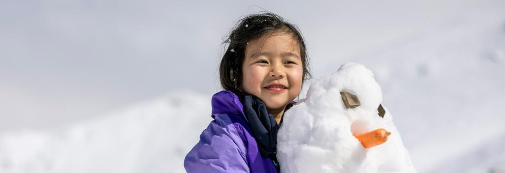 Little girl cuddling a snowman up Mt Hutt
