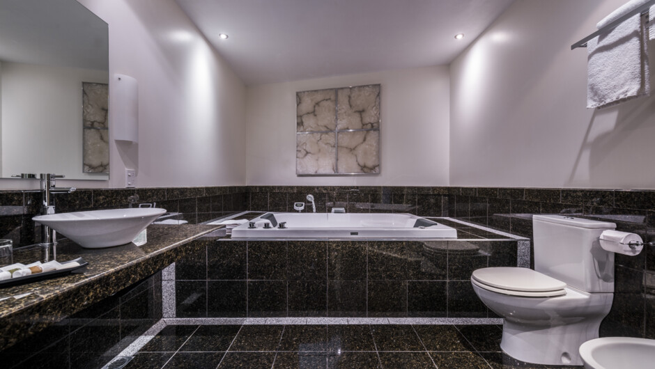 Marbled bathroom featuring a double sized indoor spa and a shower with twin massage heads