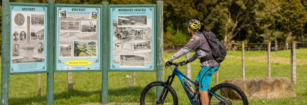 Cyclist reading historic information signs on the Fishers Track, Ruapehu