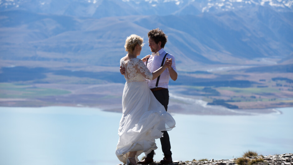 The happy couple dancing on a mountain above Lake Tekapo