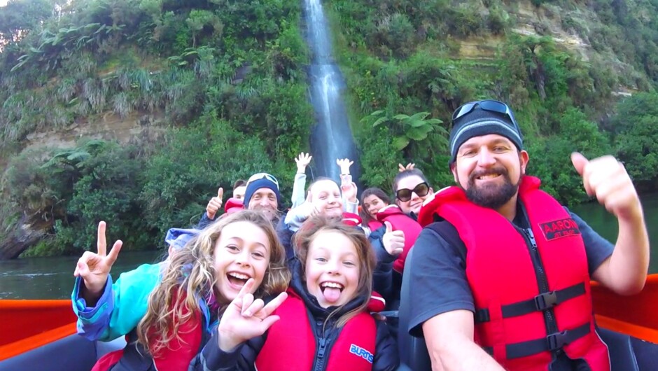 Happy clients onboard with waterfall in back ground at Camjet NZ.