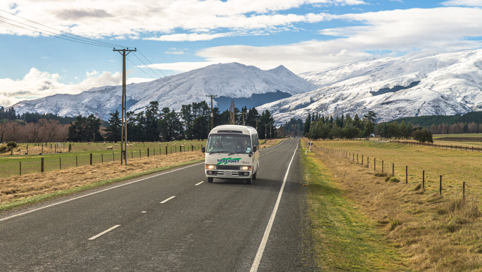 Tracknet bus on the Te Anau–Queenstown route. Daily services with optional airport pickup and connections to Milford Sound &amp; Fiordland’s Great Walks.