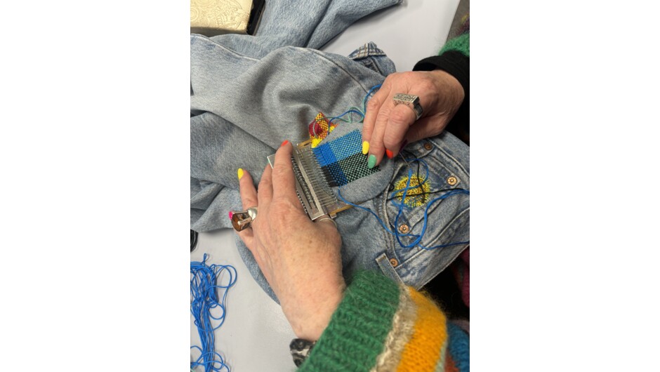 A student repairs a hole in a pair of jeans at their Visible Mending with a Speedweve Darning Loom Workshop.