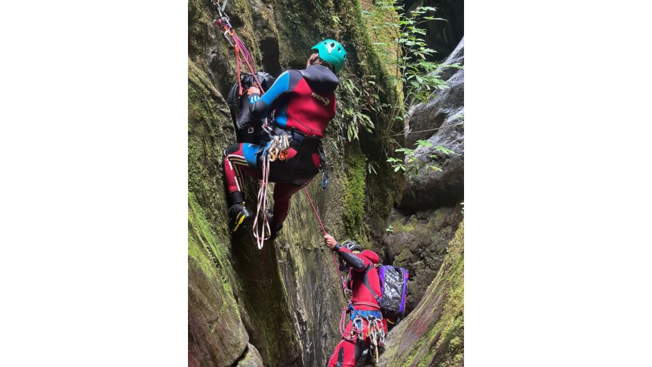 Two people rigging the drop to get it ready to abseil down