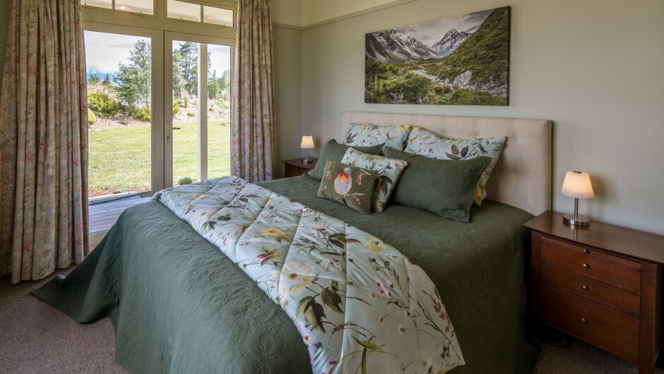 Super king bedroom with doors opening onto a private deck with hot tub &amp; mountain views