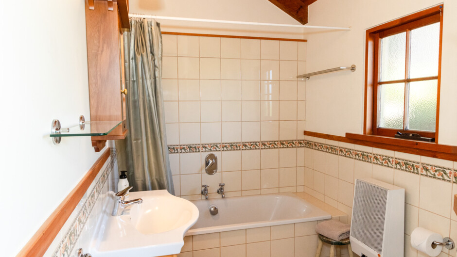 The beautifully tiled bathroom contains a shower and a bathtub for the ultimate luxury experience.